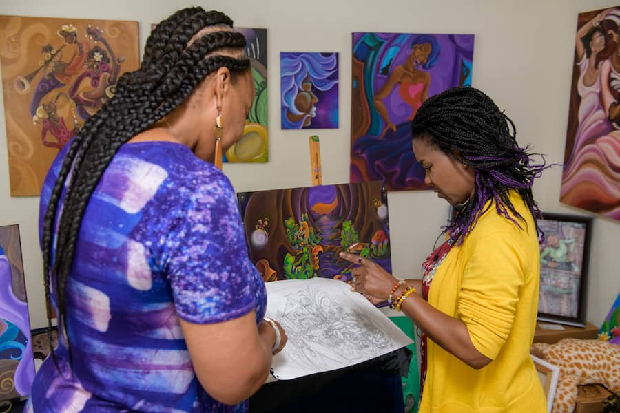 Charita Carter, executive producer at Walt Disney Imagineering and New Orleans artist, Sharika Mahdi looking at art together