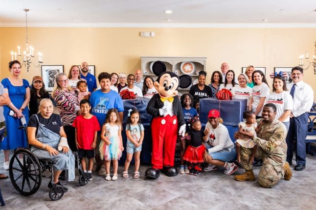 Fisher House - group photo with Mickey Mouse, Disney VoluntEARS deliver care packages for the guests of the Bethesda Fisher House