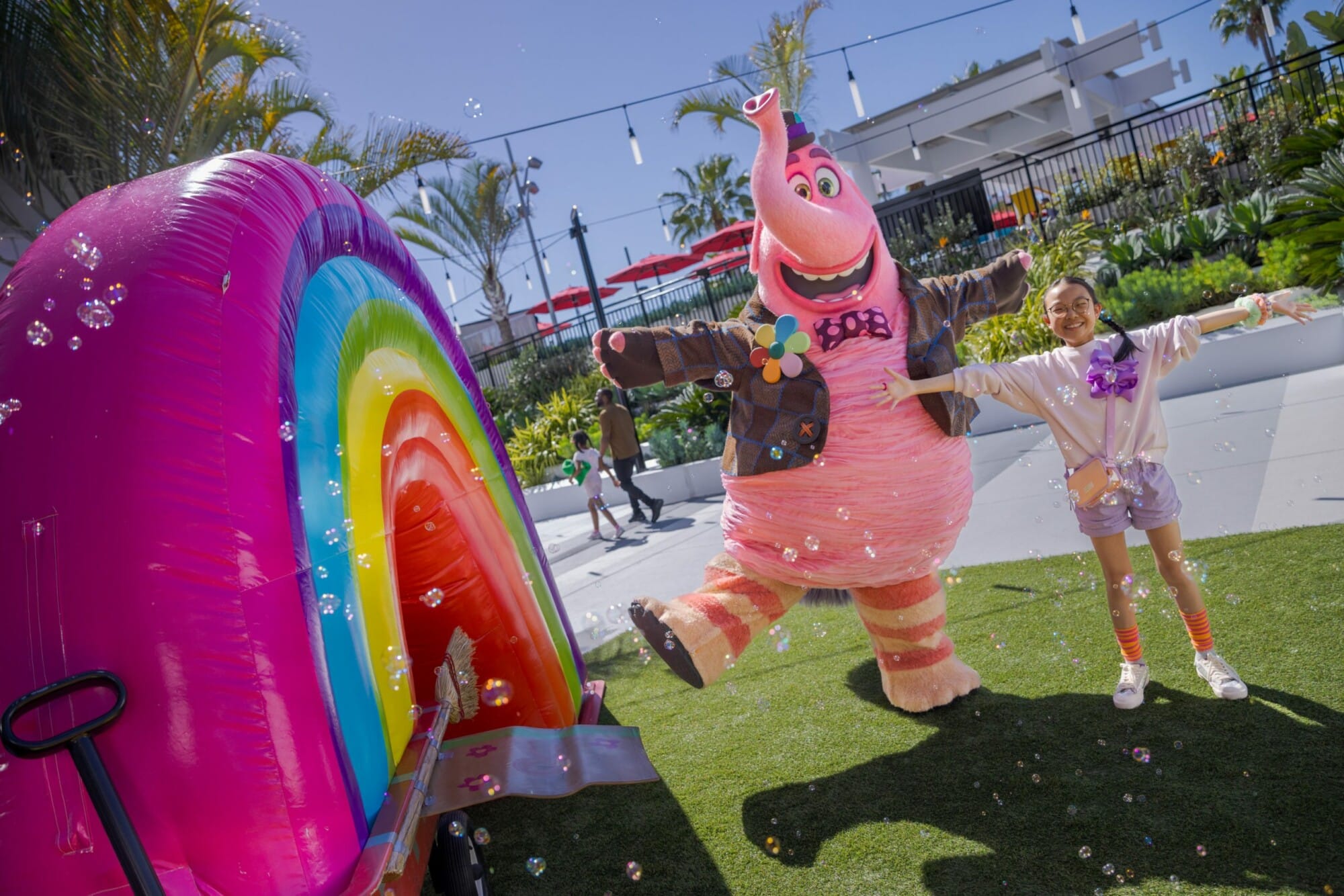 A child plays in the midst of a dozen bubbles alongside Bing-Bong.