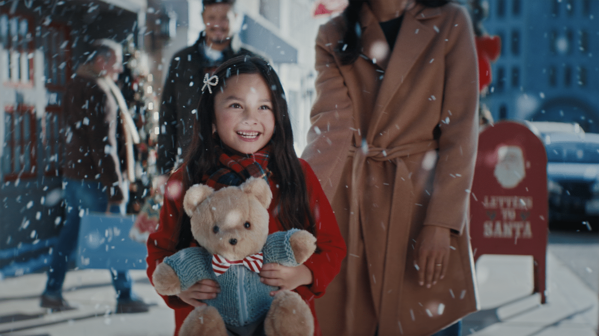 A child holds one of the teddy bears on a snowy street