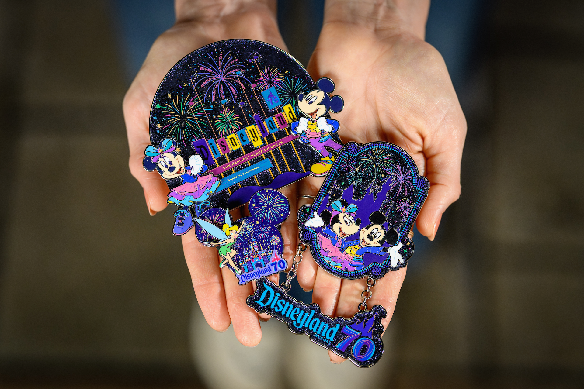 2026DLRFinaleMerchCollection5 | The Main Street Mouse Hands Hold Colorful Disneyland 70th Anniversary Souvenirs with Mickey and Minnie and Fireworks in the Background