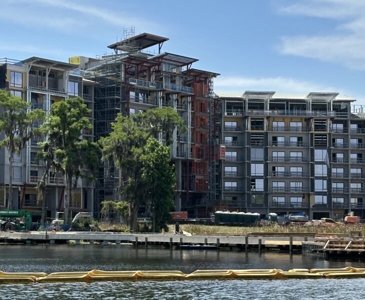IMG1323 | The Main Street Mouse Under construction multi story apartment building along a river with scaffolding and exposed framework against a blue sky