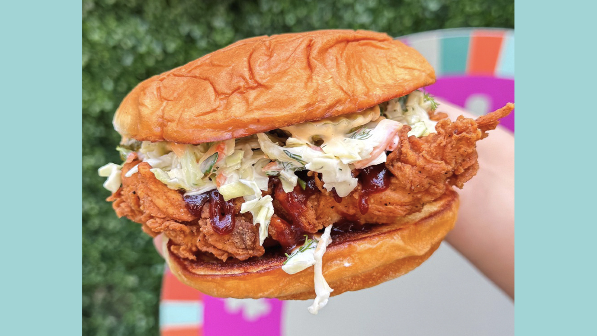 Review The Funky Chicken Sandwich at Everglazed Disney Springs | The Main Street Mouse Crispy Fried Chicken Sandwich with Creamy Coleslaw and Sauce in a Soft Bun Held Outdoors