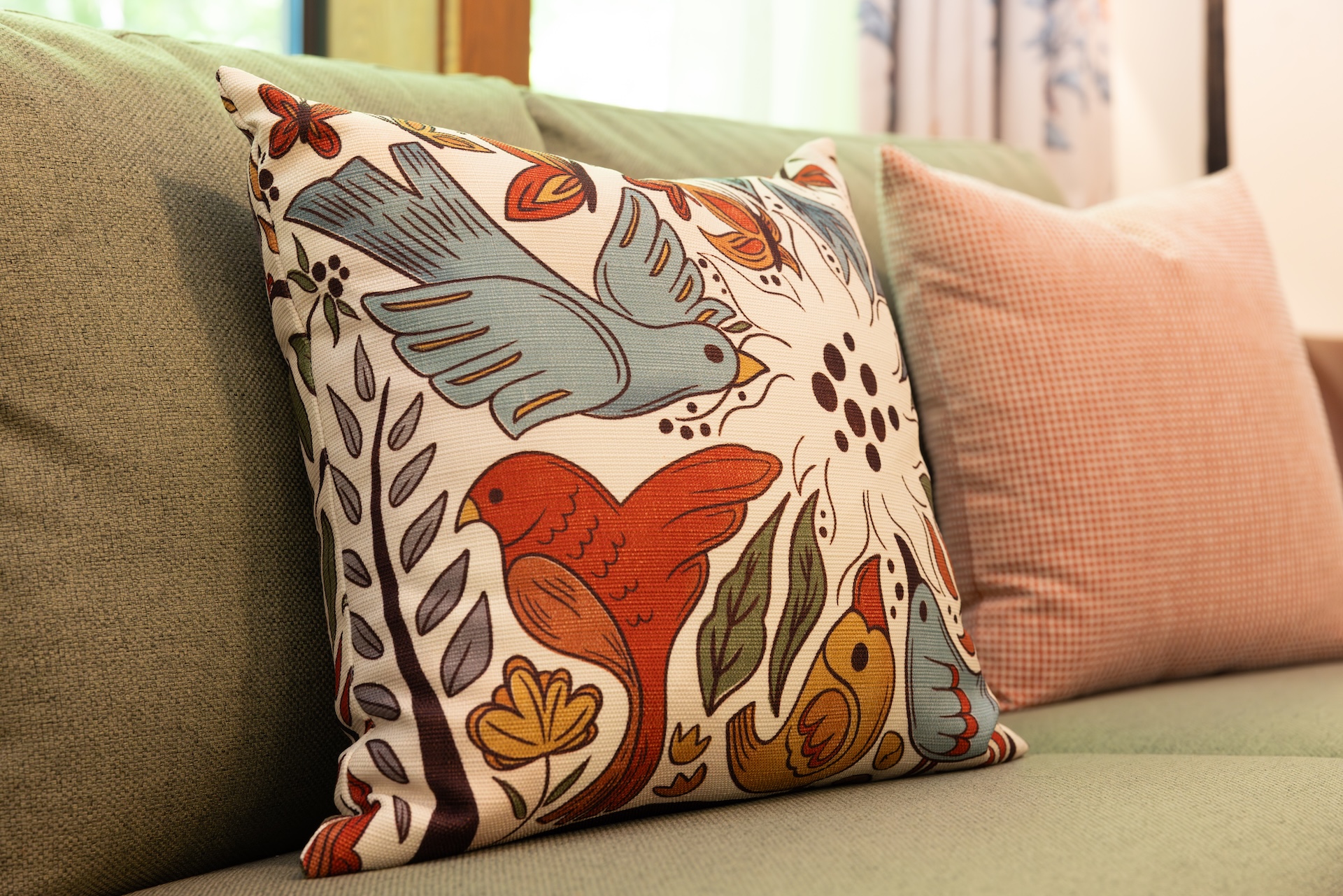 2026DVCReimaginedTreehouseVillas20 | The Main Street Mouse Colorful Decorative Throw Pillow with Birds and Flowers on a Beige Sofa Foreground Focus