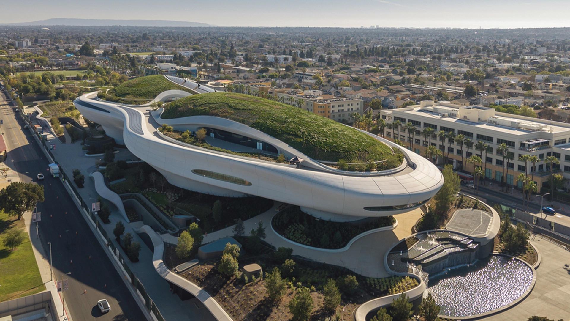 A New Hope for Storytelling Exploring the Lucas Museum of Narrative Art and the New Star Wars in Motion Exhibition | The Main Street Mouse Aerial View of a Futuristic White Building with Curving Green Roofs and Spiral Walkways Set in an Urban Landscape